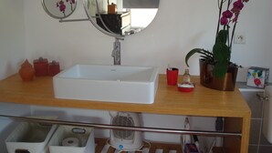 A bathroom with a white sink, a round mirror, a potted orchid, and a small red container. - THE ROOM OF MEUNIER breakfast, accès piscine (Laiz)