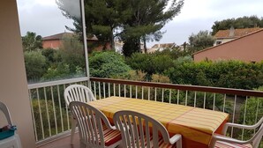 A balcony with a table and chairs, a view of greenery and buildings, and a railing. - 4-room apartment 90 m² + Terrace. Sleeps 5 Immediate proximity to beaches (Bandol)