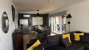 A modern living room with a dark brown sofa, a dining area with a table and chairs, and a kitchen with a refrigerator and stove. - Beautiful villa with private pool and exceptional sea views. VT-513857-A (Calpe)