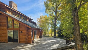 A log cabin with a covered deck and a stone chimney.