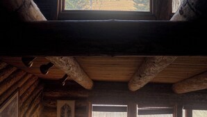 A rustic cabin interior with a large window offering a view of mountains and trees.