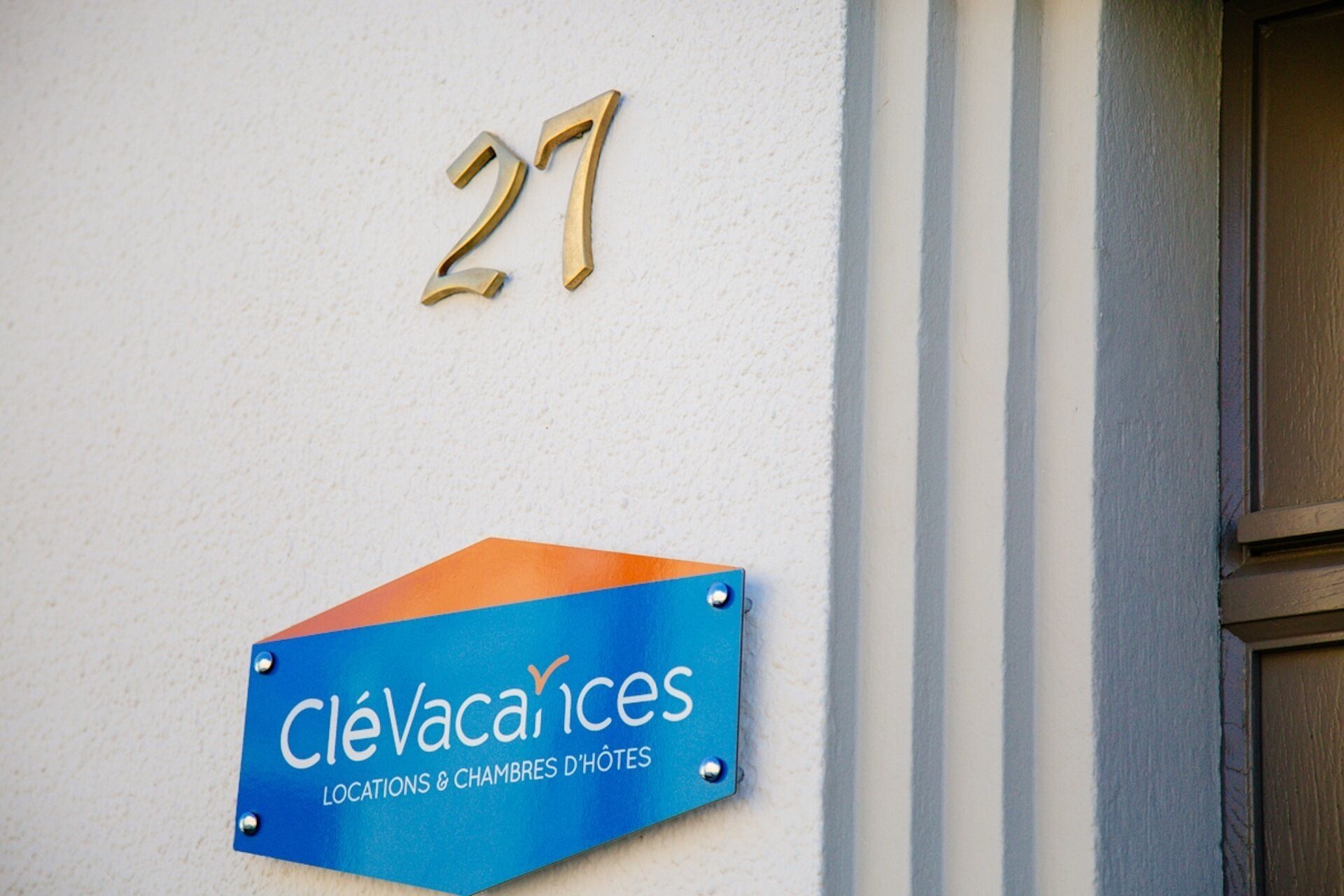 Un bâtiment portant le numéro 27 et une enseigne indiquant « CléVacances Locations & Chambres d'Hôtes ».