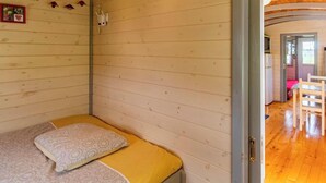 Une pièce de cabane en bois comprenant un lit, une petite table et une porte donnant sur une autre pièce.