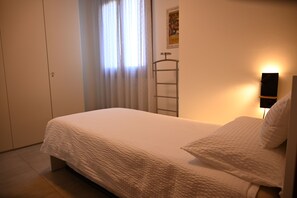 A bedroom with a bed, a wardrobe, a window with curtains, and a wall-mounted light fixture. - CASA ANDREA PALLADIO - 72 m² apartment with private parking (Monticello Conte Otto)
