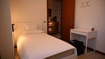 Une chambre à coucher avec un lit, un bureau, une armoire et une porte.