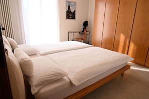 A double bed with white linens in a room with wooden flooring and a wooden wardrobe. - CASA ANDREA PALLADIO - 72 m² apartment with private parking (Monticello Conte Otto)