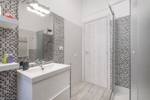 Ein modernes Badezimmer mit einem großen Spiegel, zwei Waschbecken, einer Dusche und einer Fliesenrückwand.