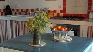 A kitchen with a white table and bench, a basket of fruit, and a gas stove. - House with enclosed garden adjacent cycle path leading to the beach. Internet (Dolus-D'oléron)