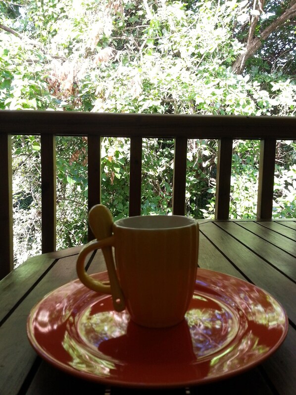 A wooden table with a red saucer and a yellow mug.