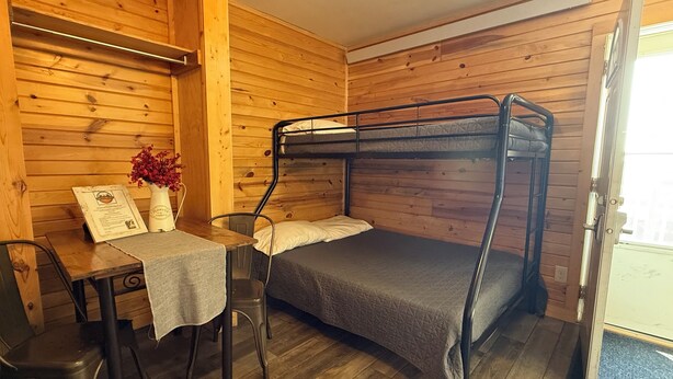 A bunk bed room with a table, chairs, and a vase of flowers. - Frenchy's Hideaways Cabin #3 (Custer)