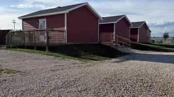 A red building with a gravel driveway and a wooden fence.