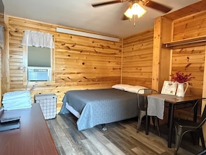 A wooden cabin room with a bed, a table, and a chair. - Frenchy's Hideaways Cabin #3 (Custer)