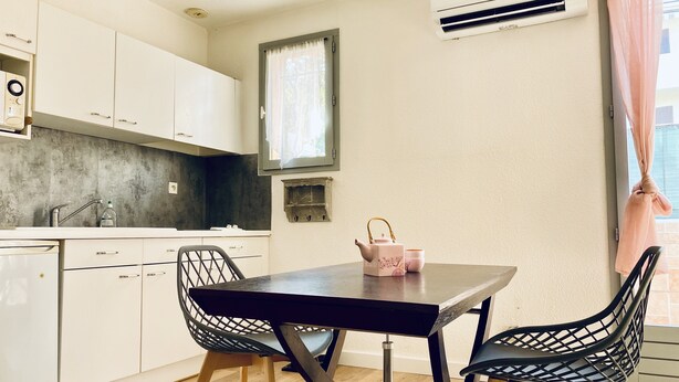 A modern kitchen with white cabinets, a wooden countertop, and a dining table with chairs. - T2 apartment 100 meters bright, fully furnished baths (Gréoux-Les-Bains)