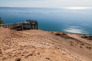 Uma praia de areia com uma plataforma de madeira que oferece vista para o mar.