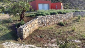 A modern red building with a stone wall and a tree in a landscaped area. - Villa Cape Town design and tranquility in an enchanting (kokkino chorio)