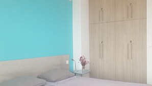 A bedroom with a bed, a nightstand, a vase with flowers, and a wardrobe. - Villa Cape Town design and tranquility in an enchanting (kokkino chorio)