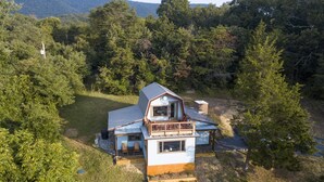 Ein zweigeschossiges Haus mit Balkon, umgeben von dichtem Wald.