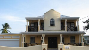 Uma casa de dois andares com varanda, garagem e portão fechado.