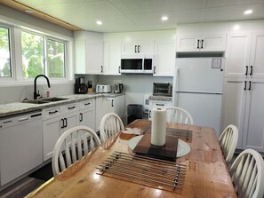 A modern kitchen with white cabinets, a wooden dining table, and a built-in microwave. - Unique Air-Conditioned Balsam Lake Waterfront,5 Bedrooms, 3 Baths, Dog friendly. (Kirkfield)