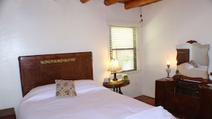 A bedroom with a wooden headboard, a bedside table with a lamp, a dresser, and a window with blinds. - 3  Bedroom Home With Lovely Vigas And Wood Floors - 3.5 Miles To Santa Fe Plaza! (Santa Fe)