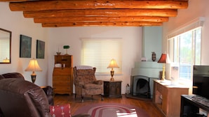 A cozy living room with a fireplace, wooden ceiling beams, a leather sofa, and two lamps. - 3  Bedroom Home With Lovely Vigas And Wood Floors - 3.5 Miles To Santa Fe Plaza! (Santa Fe)