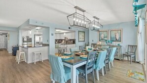 Un comedor amplio con una isla central, sillas azul claro e iluminación colgante moderna.