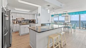Una cocina moderna con una isla grande, armarios blancos y vista al océano.