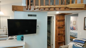 Una cocina moderna con estufa integrada, un televisor de pantalla plana grande y una encimera blanca.