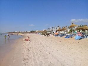 A beach with umbrellas and lounge chairs.