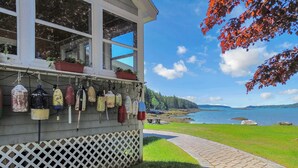 A building with a wooden lattice front, a pathway leading to a body of water, and buoys hanging on the exterior wall.