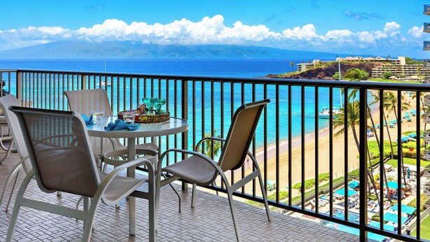 Ein Balkon mit Meerblick, ein Esstisch mit Stühlen und eine kleine Gartenanlage.