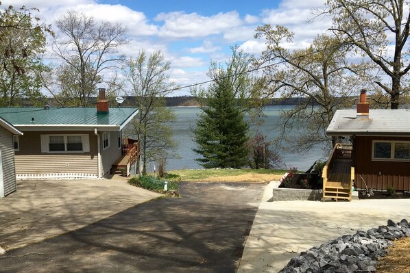 A residential property with a driveway leading to a house with a green roof, a wooden deck, and a view of a lake. - Gather at family-friendly Shelter Point on KY Lake (Murray)