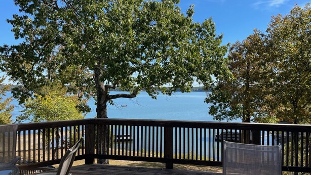 Une terrasse en bois offrant une vue sur un lac et des arbres.