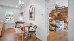 A dining area with a wooden table and chairs, a chandelier, and a view of the outdoors.