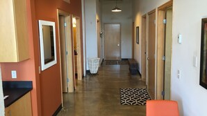 A hallway with wooden doors, a bench, a trash bin, and a patterned rug. - Cozy Loft U of M Dinkytown (Minneapolis)