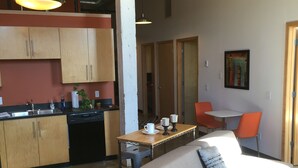 A compact living space with a kitchenette, a dining area with a table and chairs, and a sofa with a cushion. - Cozy Loft U of M Dinkytown (Minneapolis)