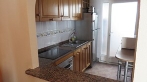 A kitchen with wooden cabinets, a granite countertop, a stainless steel sink, and a refrigerator. - Beautiful house in urb. international (Gran Alacant)