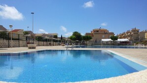 A clear swimming pool with a tiled edge, surrounded by a pebble-lined deck. - Beautiful house in urb. international (Gran Alacant)