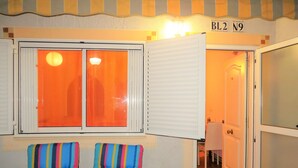 A room with a large window, a door, and two striped chairs. - Beautiful house in urb. international (Gran Alacant)
