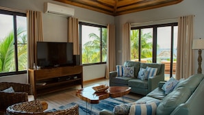 A living room with a television, sofas, and wicker furniture. - Private Island Beachfront Villa 1 Min From Village (Placencia)