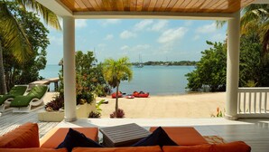 A covered outdoor seating area with a view of a beach and the sea. - Private Island Beachfront Villa 1 Min From Village (Placencia)