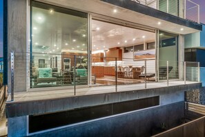Un immeuble résidentiel moderne doté d’un balcon, de grandes fenêtres et d’un espace cuisine ouvert.