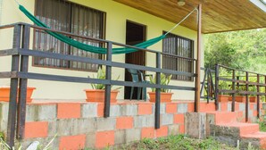 A building with a wooden porch, concrete steps, and potted plants. - Butterfly Cabin - Ocean View-  San Ramon and Esparza (San Ramon)