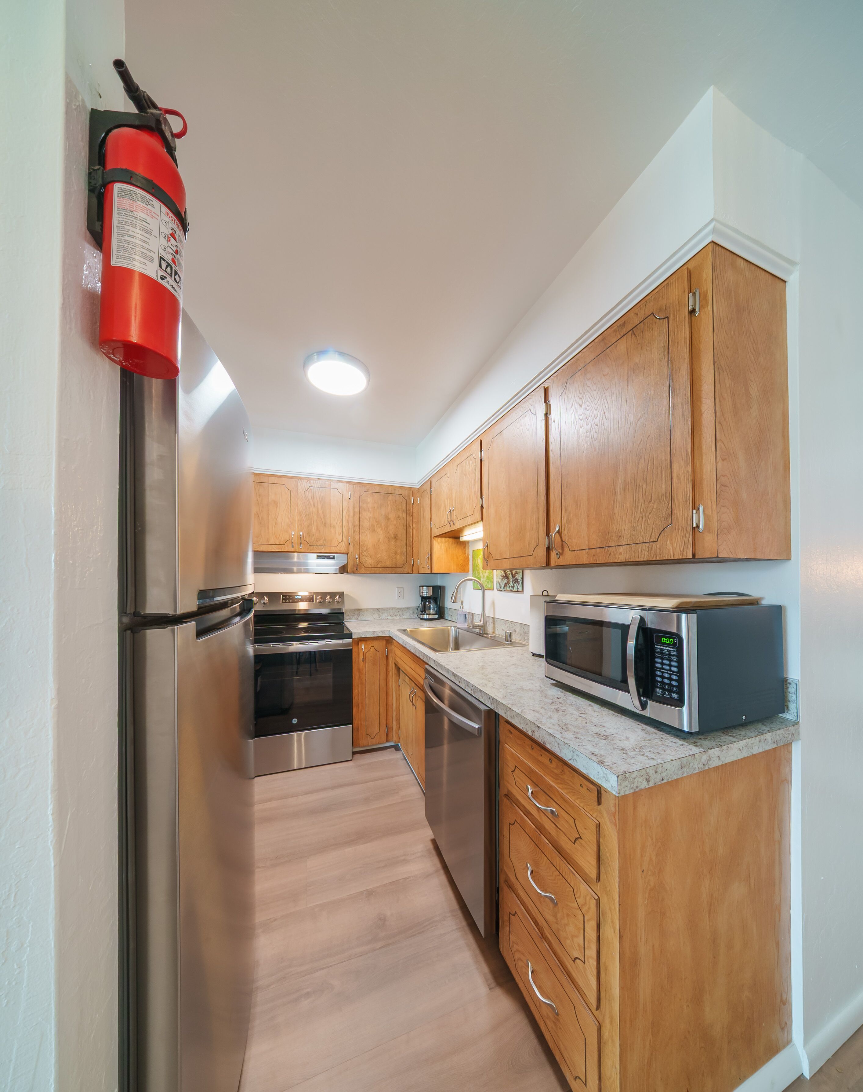 A modern kitchen with stainless steel appliances, wooden cabinets, and a built-in microwave.