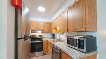 A modern kitchen with stainless steel appliances, wooden cabinets, and a built-in microwave.