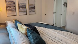 Un dormitorio con una cama, almohadas y tres cuadros en la pared.