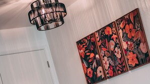 Un comedor con una puerta blanca, sillas negras, una mesa de madera y una lámpara colgante negra.