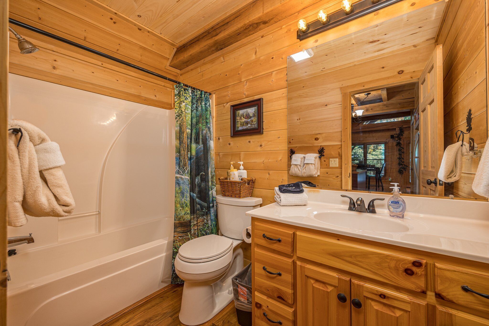 A wooden cabin bathroom with a bathtub, toilet, and vanity.