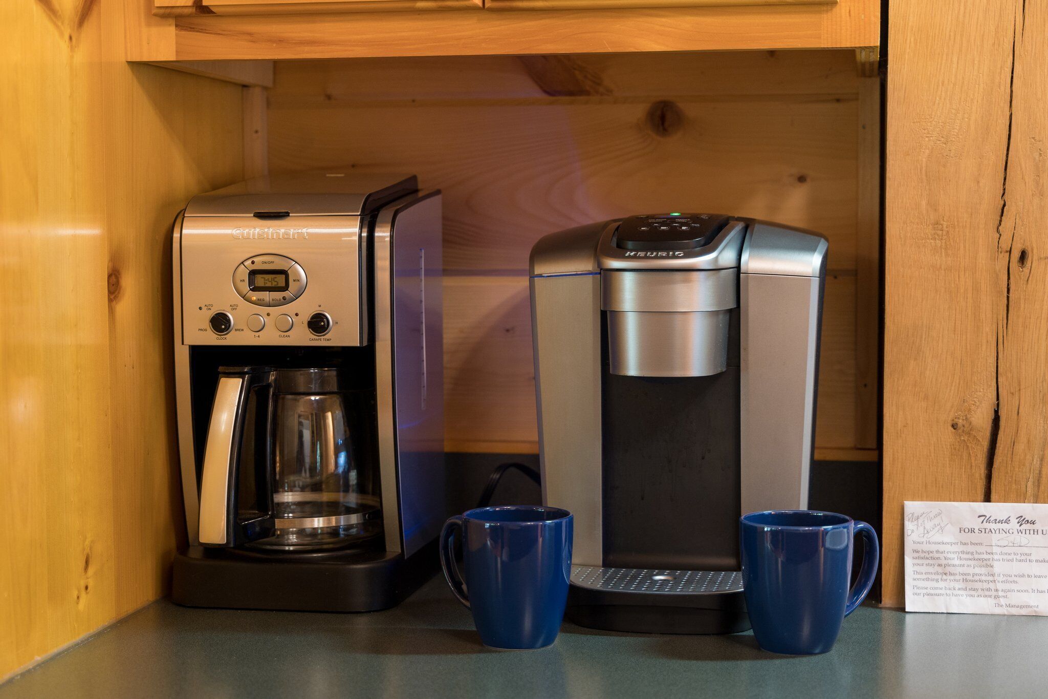 Una cafetera con pantalla digital y una máquina de espresso separada, ambas sobre una encimera de madera.