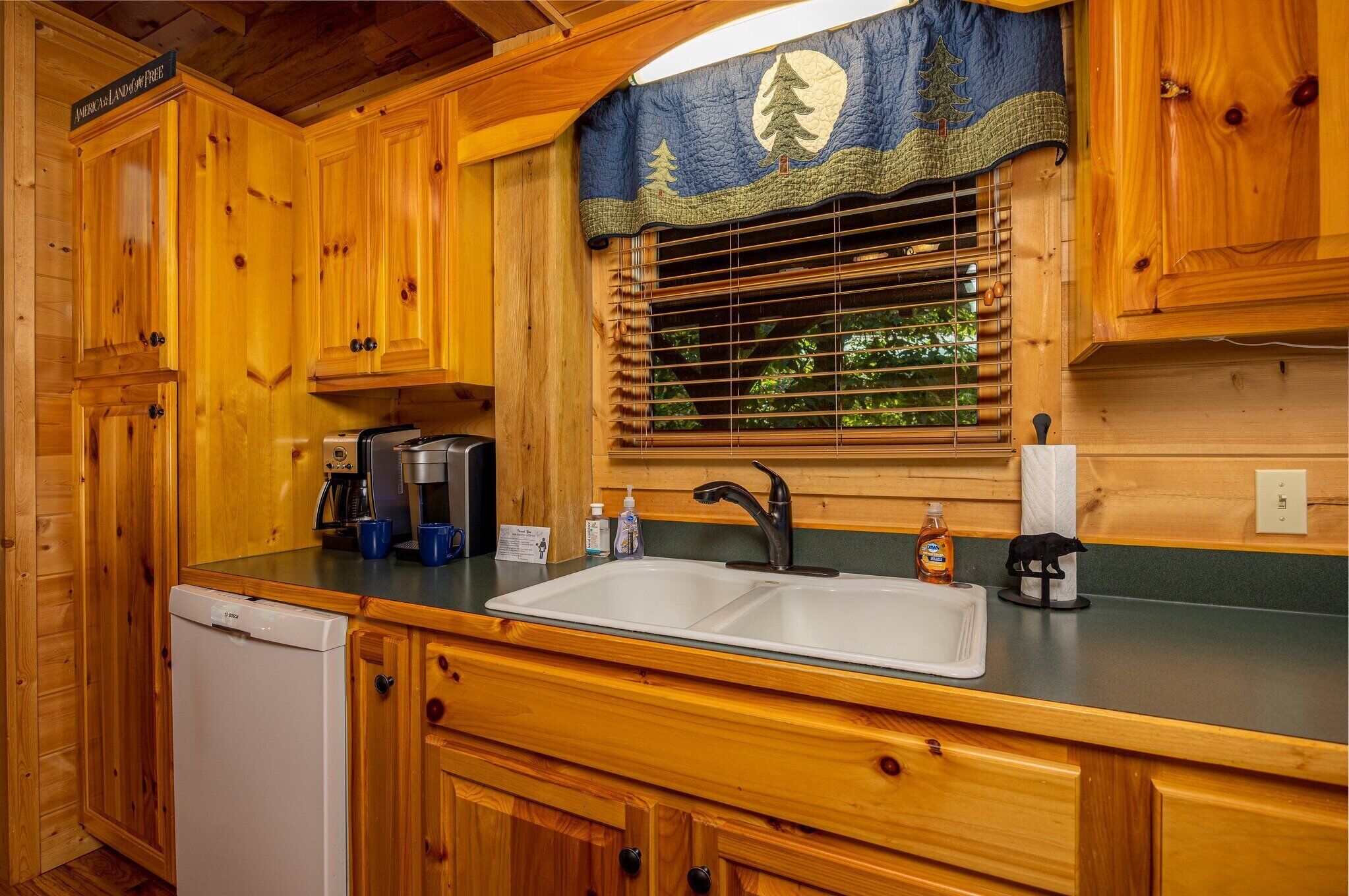 Une cuisine rustique aménagée dans une cabane en bois, comprenant un évier, une machine à café et un lave-vaisselle.